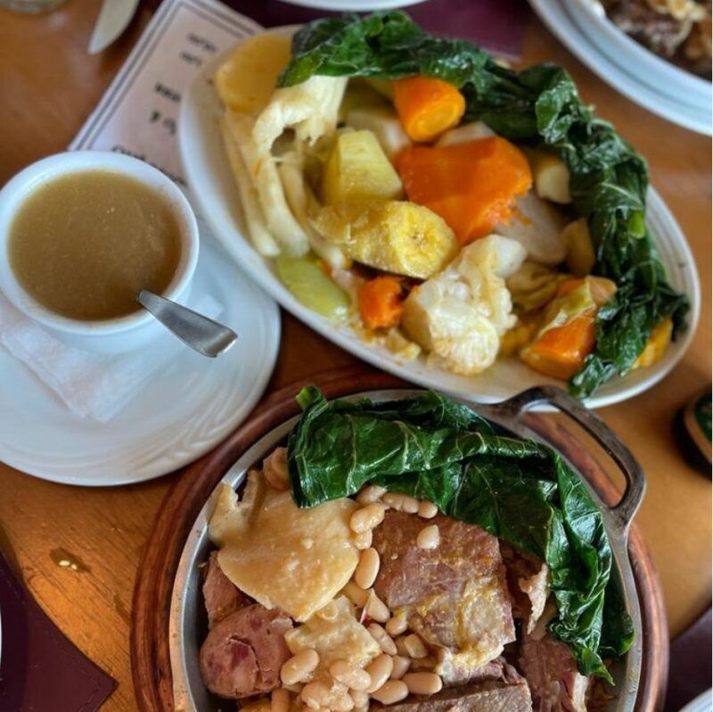 platos de carne y verduras y una taza de caldo con cuchara al lado, coida típica portuguesa