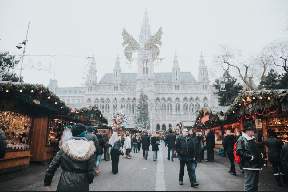 personas en una calle con paradas navideñas y edificio al fondo