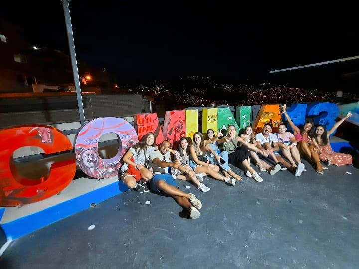 grupo de viajeros de weroad delante del cartel de la comuna 13 en colombia, destino a donde viajar en febrero