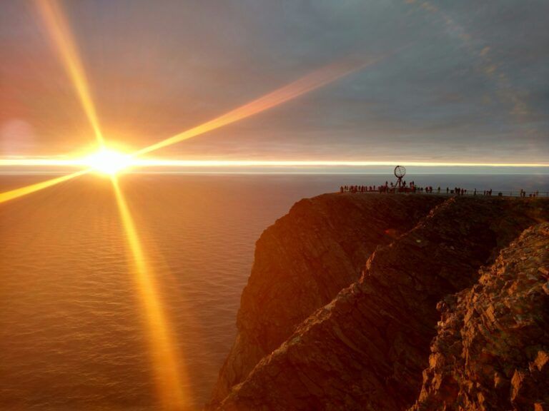 sol de medianoche en cabo norte, se vislumbra el monumento en forma de semiesfera y el acantilado