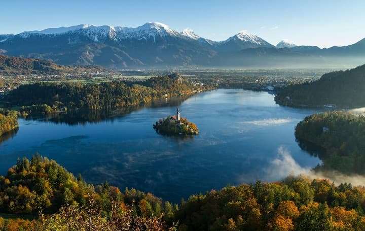 islote en el lago de bled con montañas detrás