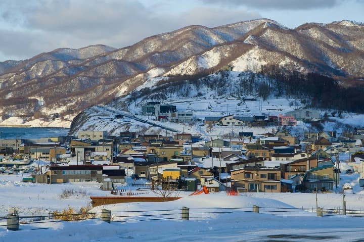 Paisaje de montaña con nieve y casas en Hokkaido.