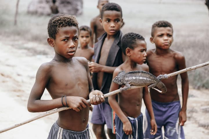 niños con un palo y un camaleón en madagascar