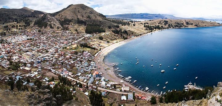 Vision aerea de Copacabana en Bolivia, mar, edificios y montaña al fondo.