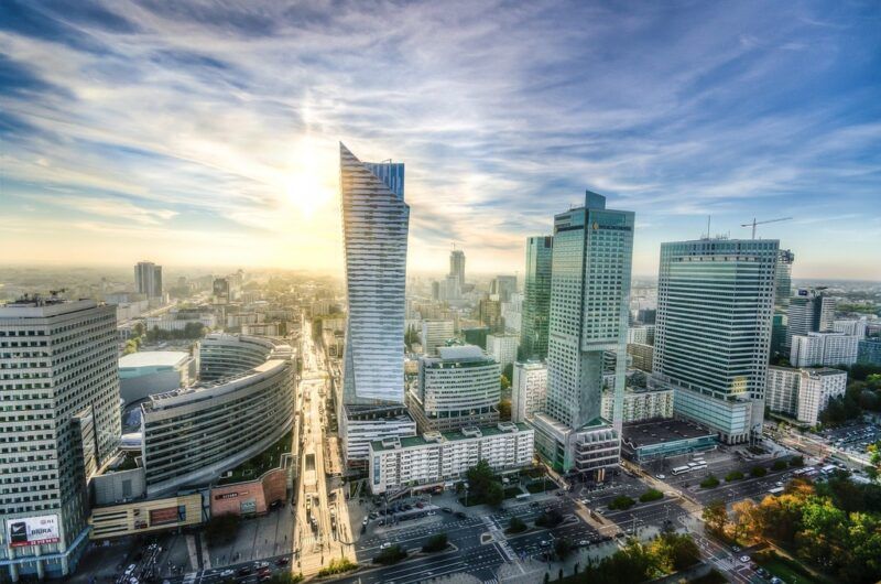 Skyline moderno de Varsovia al atardecer, destacando sus rascacielos de cristal bajo un cielo luminoso.