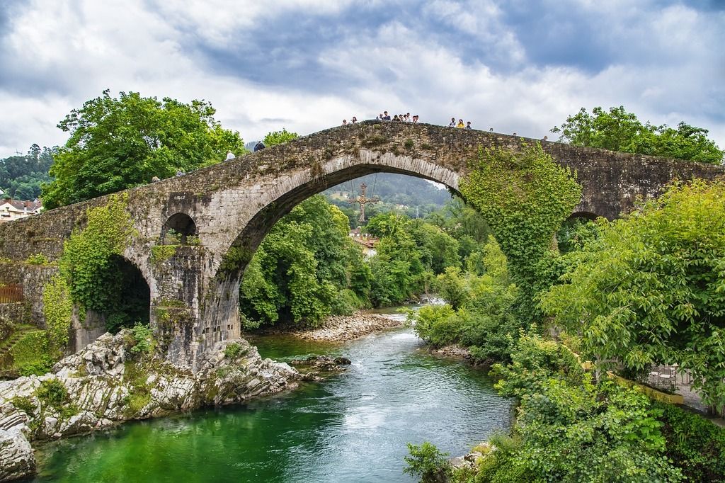 Puente Romano de Cangas de Onís, Asturias – Icónico puente de piedra cubierto de vegetación sobre un río de aguas cristalinas.