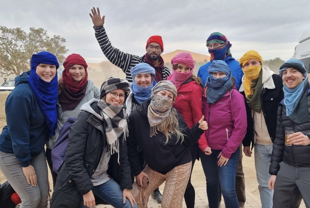 Grupo de viajeros WeRoad con turbantes en el desierto de Marruecos 