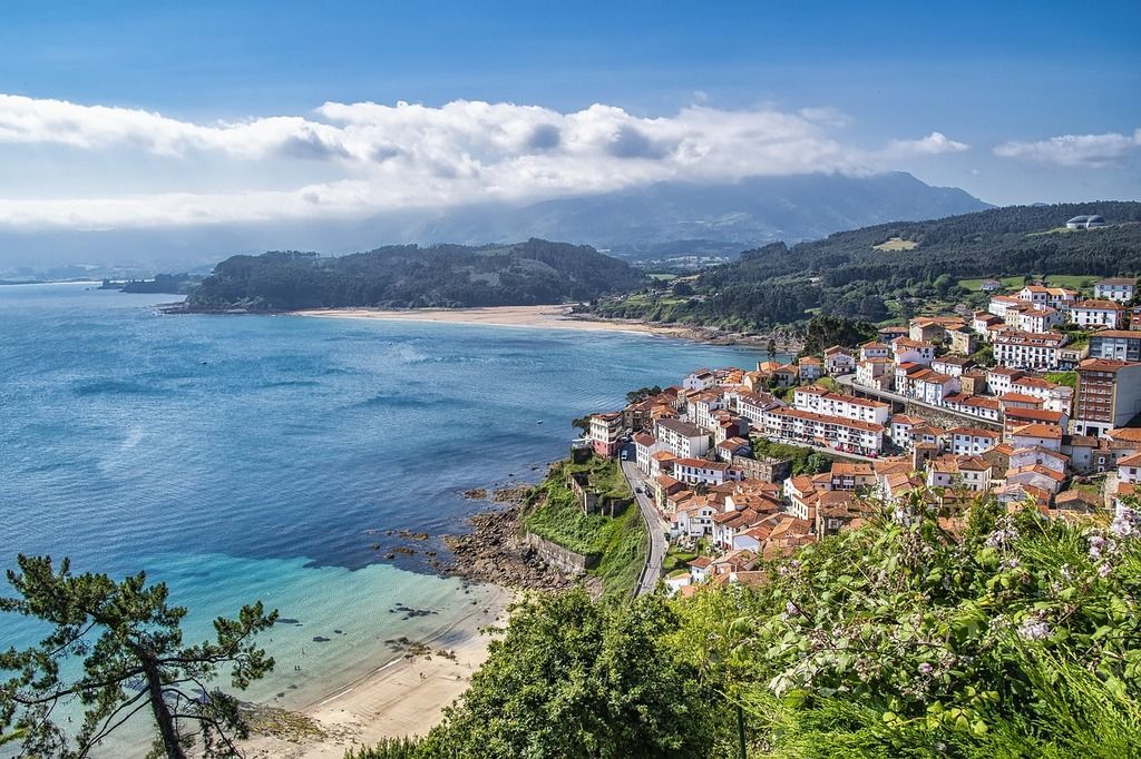 Pueblo costero de Asturias con vistas al mar Cantábrico – Casas con tejados rojizos en un paisaje costero rodeado de montañas y playas.