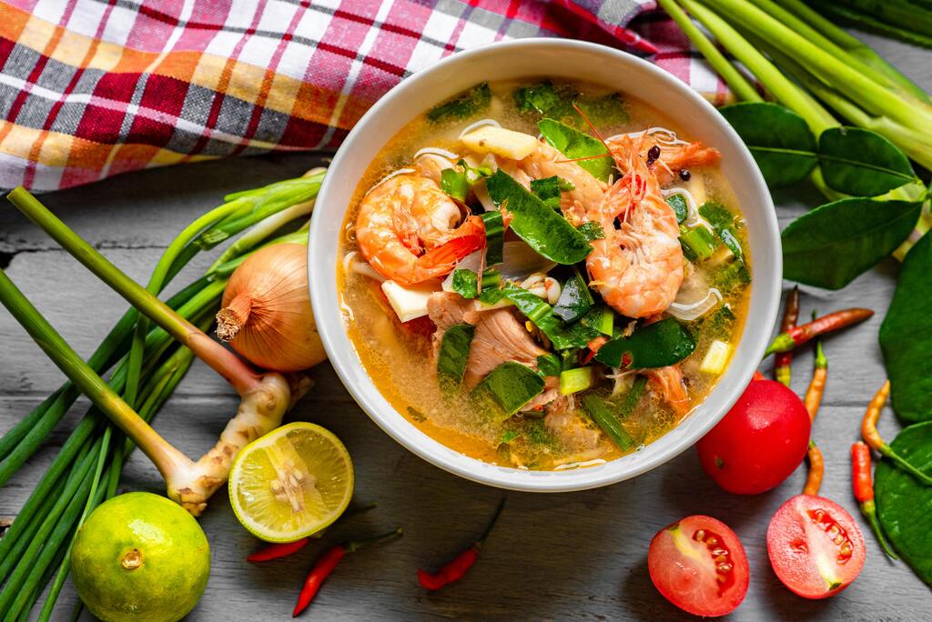 Sopa tailandesa Tom Yum con camarones, hierbas aromáticas y verduras frescas.