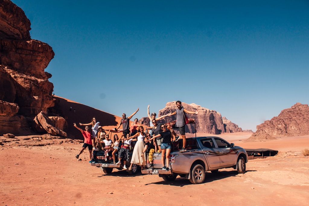 Grupo de viajeros en un 4x4 en el desierto de Wadi Rum, Jordania, explorando la aventura en un safari por las dunas.