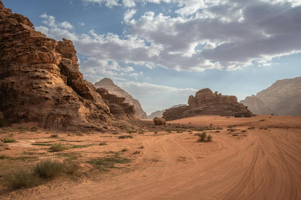 Paisaje desértico en Wadi Rum, Jordania con montañas de arenisca y cielo azul con nubes dispersas.