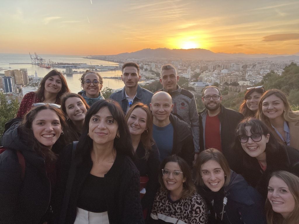 Grupo de viajeros en un viaje organizado a Asturias – Un grupo sonriente disfruta de la puesta de sol con vistas panorámicas de la costa asturiana en un viaje de grupo WeRoad.