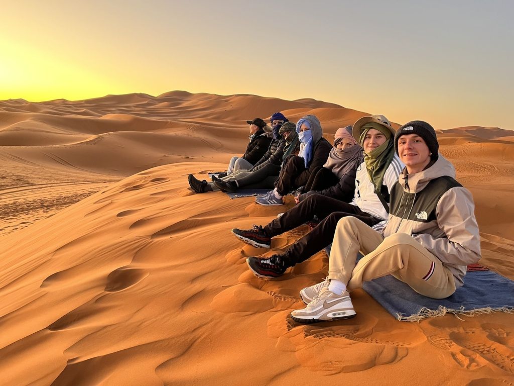 Grupo de viajeros WeRoad en Túnez, disfrutando del atardecer en el desierto tunecino.