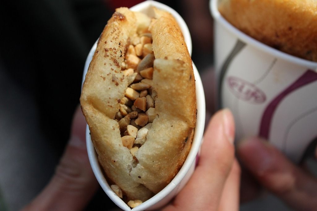 Un hotteok, un dulce coreano relleno de azúcar y frutos secos, servido en un vaso de papel.