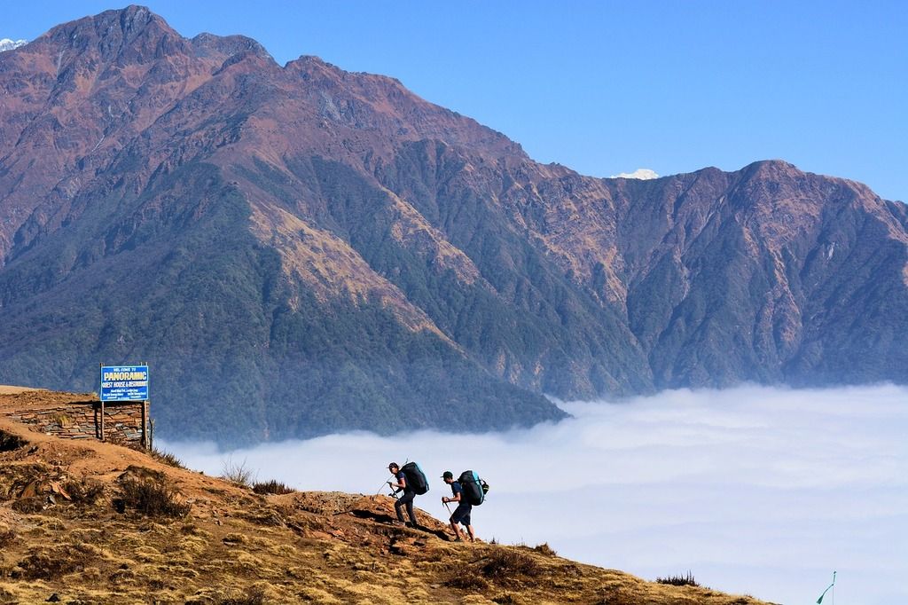 Dos excursionistas subiendo un sendero con vistas panorámicas de las montañas en Nepal.