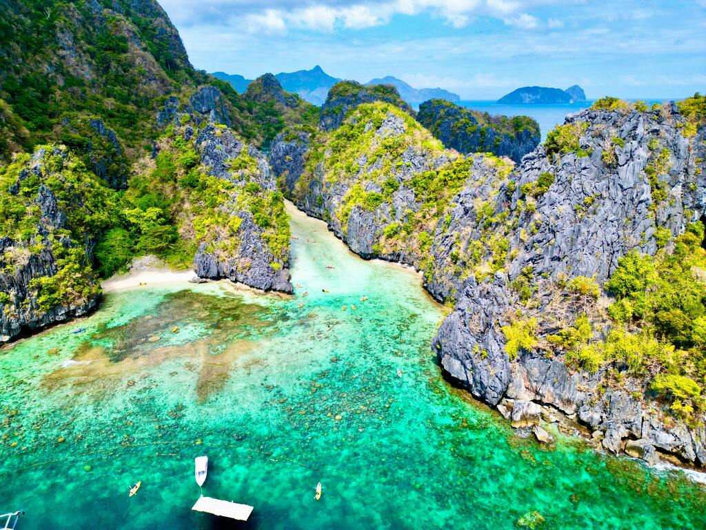 Vista aérea de una laguna escondida en El Nido, Filipinas, rodeada de acantilados verdes.
