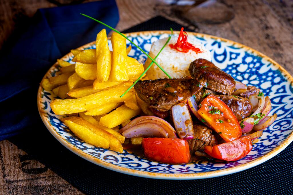 Lomo saltado peruano servido con papas fritas y arroz blanco.