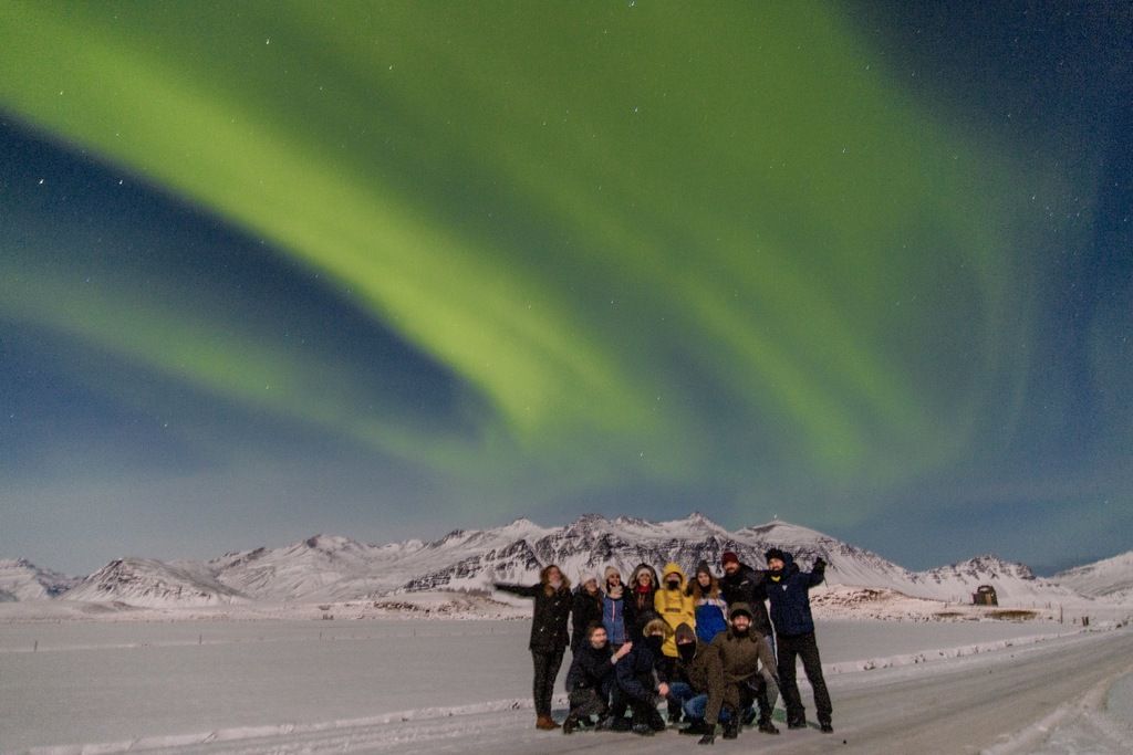 Auroras boreales sobre un grupo de viajeros en un paisaje nevado