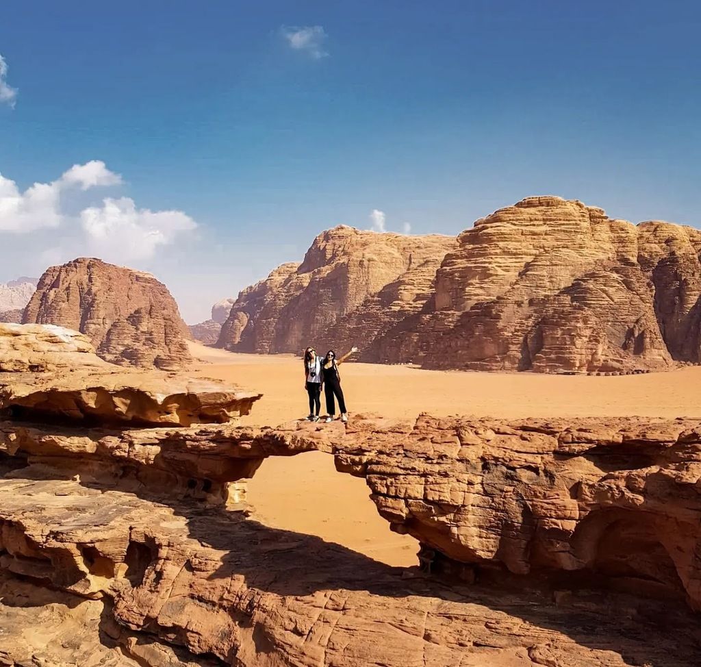 Dos personas sobre un puente natural en el desierto de Wadi Rum
