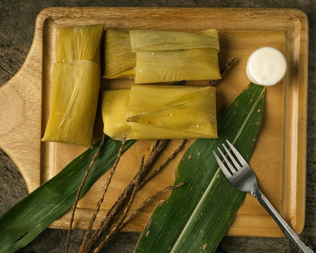  Tamales envueltos en hojas de maíz servidos con crema