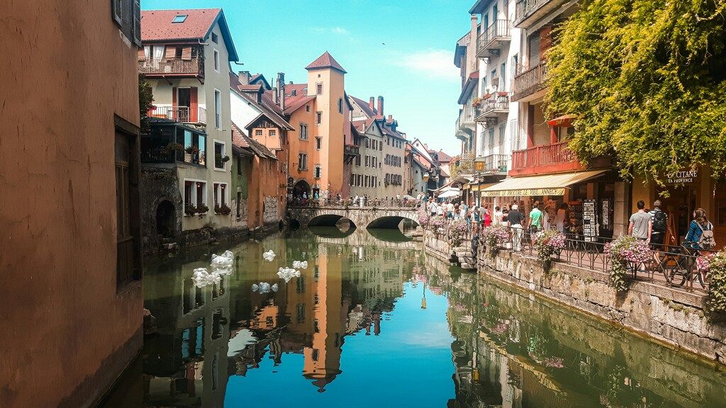 Casas de colores junto a los canales del casco antiguo de Annecy, con cisnes nadando.