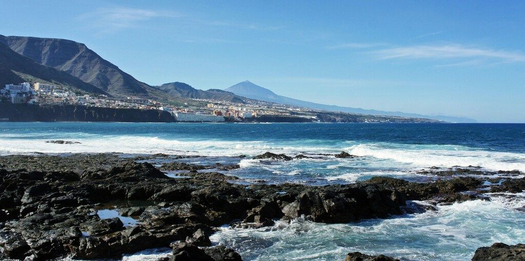 Punta del Hidalgo y vista del Teide desde la costa norte de Tenerife con mar agitado y rocas volcánicas