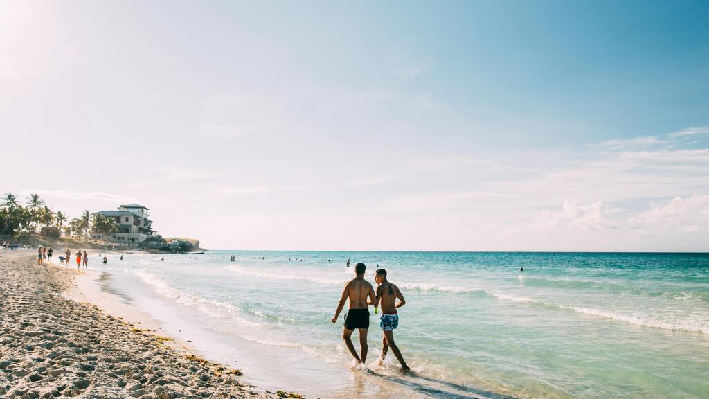 Pareja caminando por la playa de arena blanca en Cuba bajo el sol