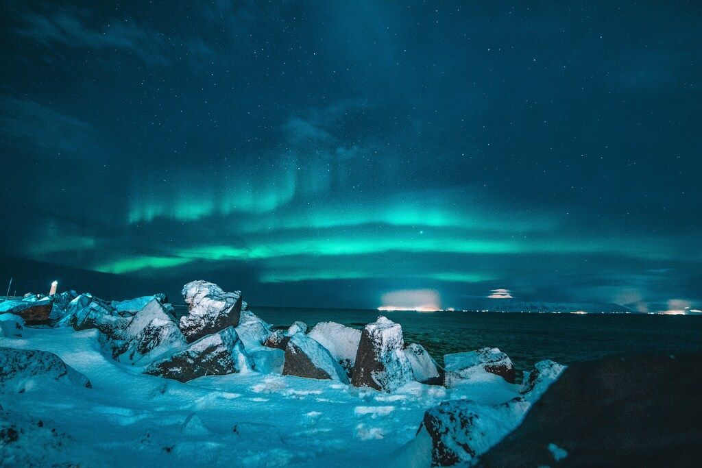 Aurora boreal sobre un paisaje costero nevado en Islandia