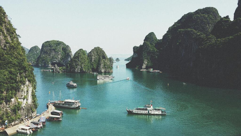 Barcos turísticos en la Bahía de Ha Long, Vietnam, rodeados de formaciones rocosas cubiertas de vegetación.