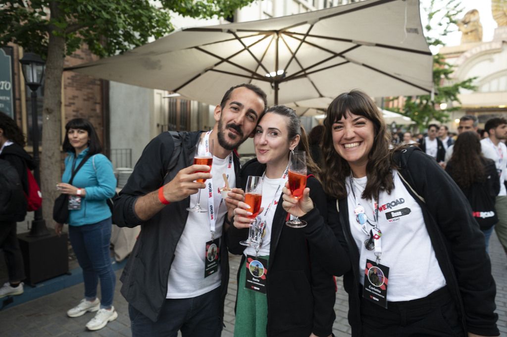 Tres jóvenes sonrientes brindando con cócteles durante un evento de la comunidad WeRoad.