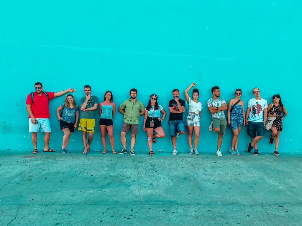 Grupo de viajeros posando con actitud relajada frente a una pared azul vibrante durante un viaje de grupo.
