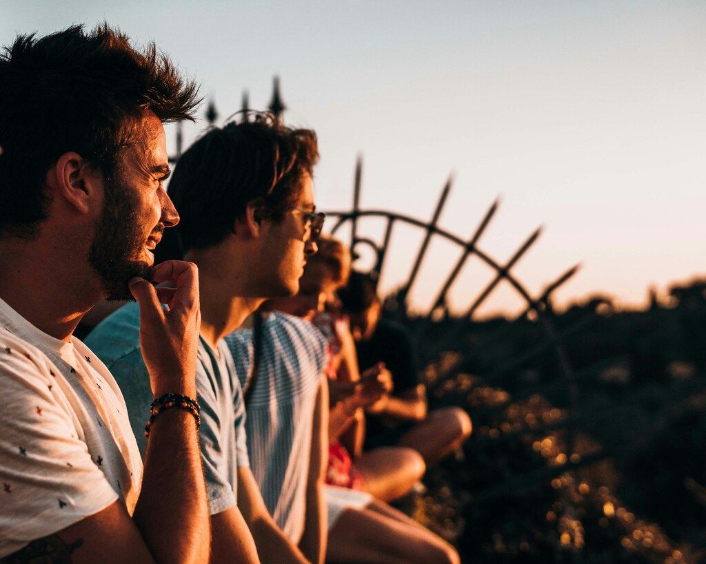 Jóvenes contemplando el atardecer desde un mirador, disfrutando de un momento de calma durante un viaje.