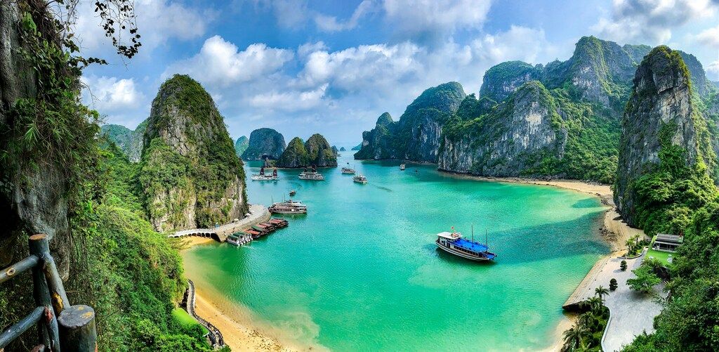 Vista panorámica de la bahía de Ha Long con formaciones kársticas y barcos navegando en aguas turquesa.