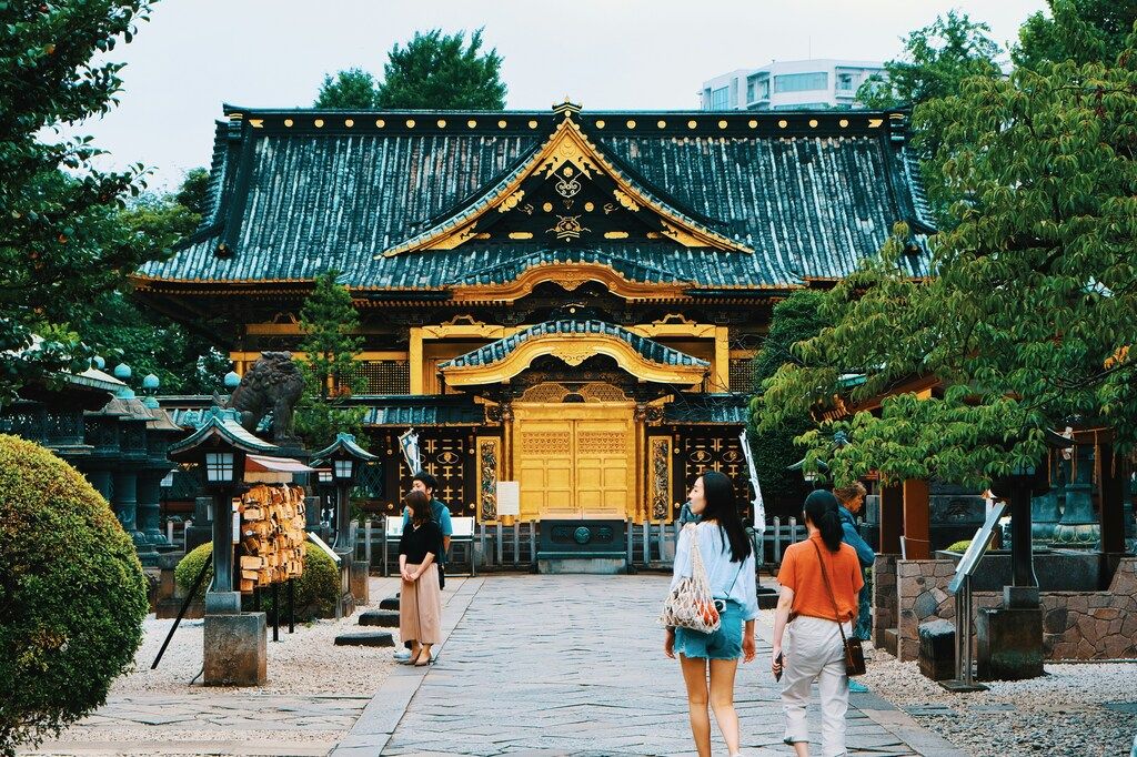 Viajeros paseando frente al histórico santuario Ueno Toshogu, decorado en oro.