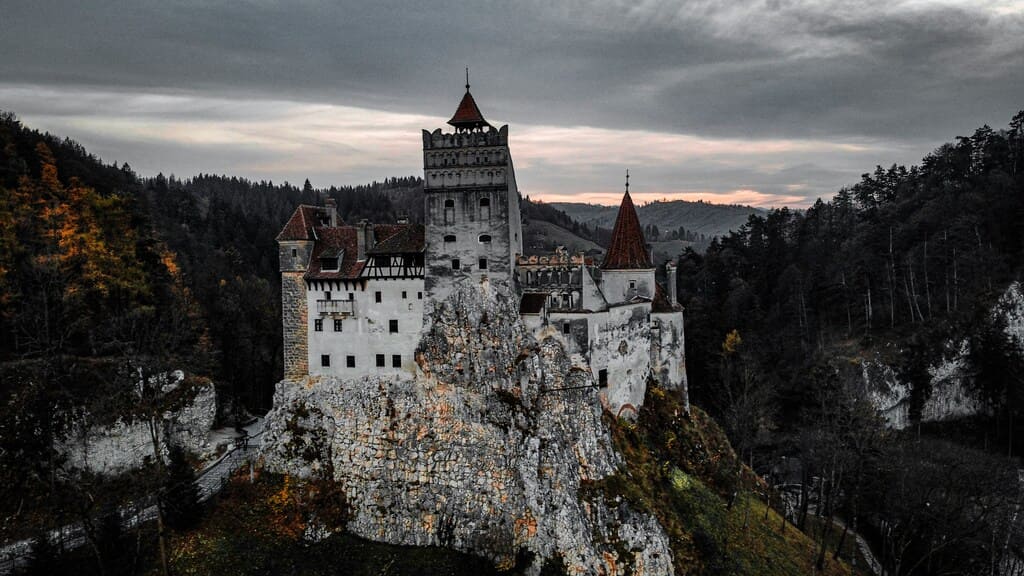 Castillo de Bran al atardecer, rodeado de bosque y montañas