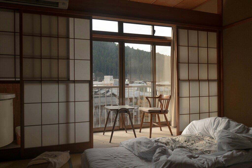 Interior de un ryokan con puertas corredizas de papel y vistas a las montañas desde el balcón.
