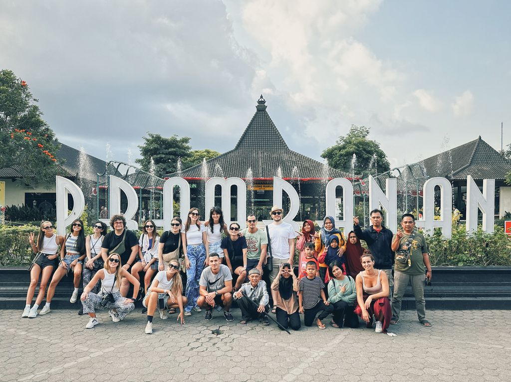 Grupo de viajeros de WeRoad y locales posando frente al cartel de Prambanan, uno de los templos más famosos de Indonesia.