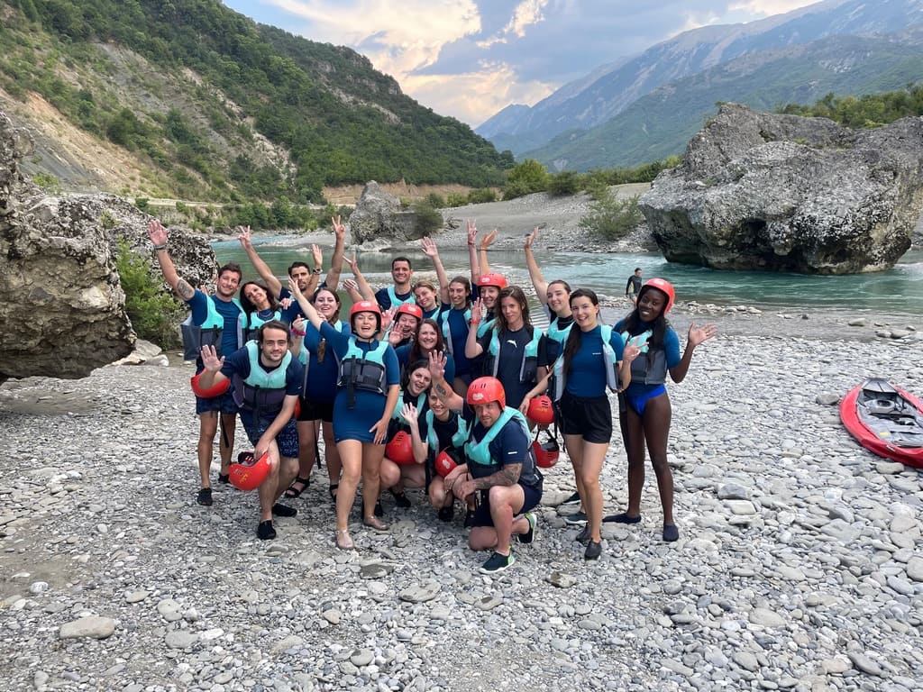 Grupo de viajeros de WeRoad sonrientes posando con chalecos salvavidas y cascos junto al río Osum, listos para una aventura de rafting en Albania.