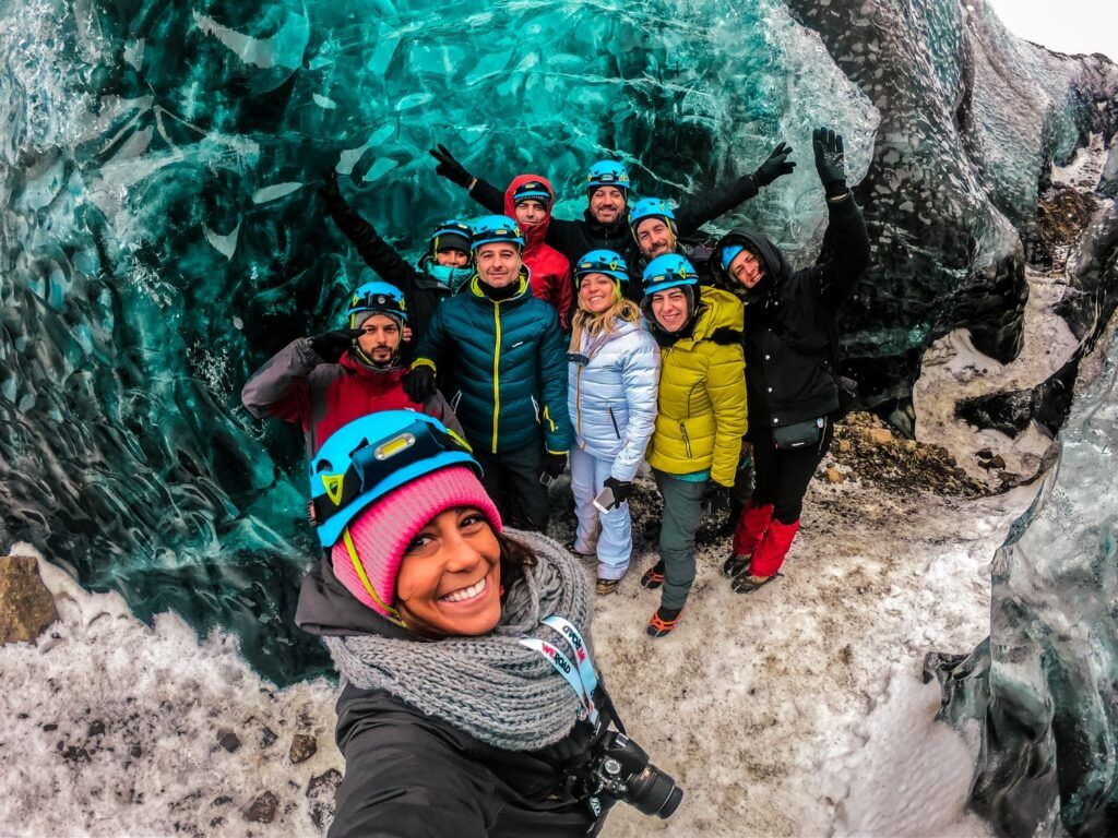 Grupo de viajeros sonrientes posando dentro de una cueva de hielo durante un viaje de WeRoad en Islandia.