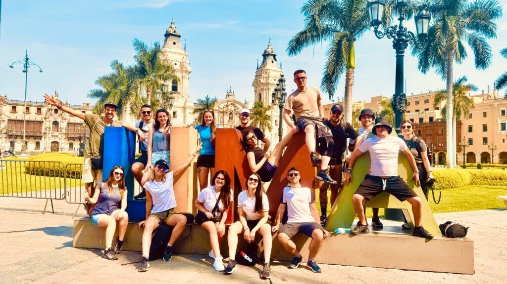 Un grupo de viaje de WeRoad posando sobre las letras de "LIMA" en la Plaza de Armas en Perú.