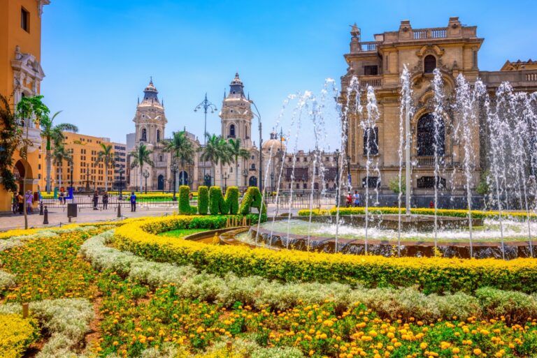 Fuente con flores y edificios históricos en la Plaza de Armas de Lima, Perú.