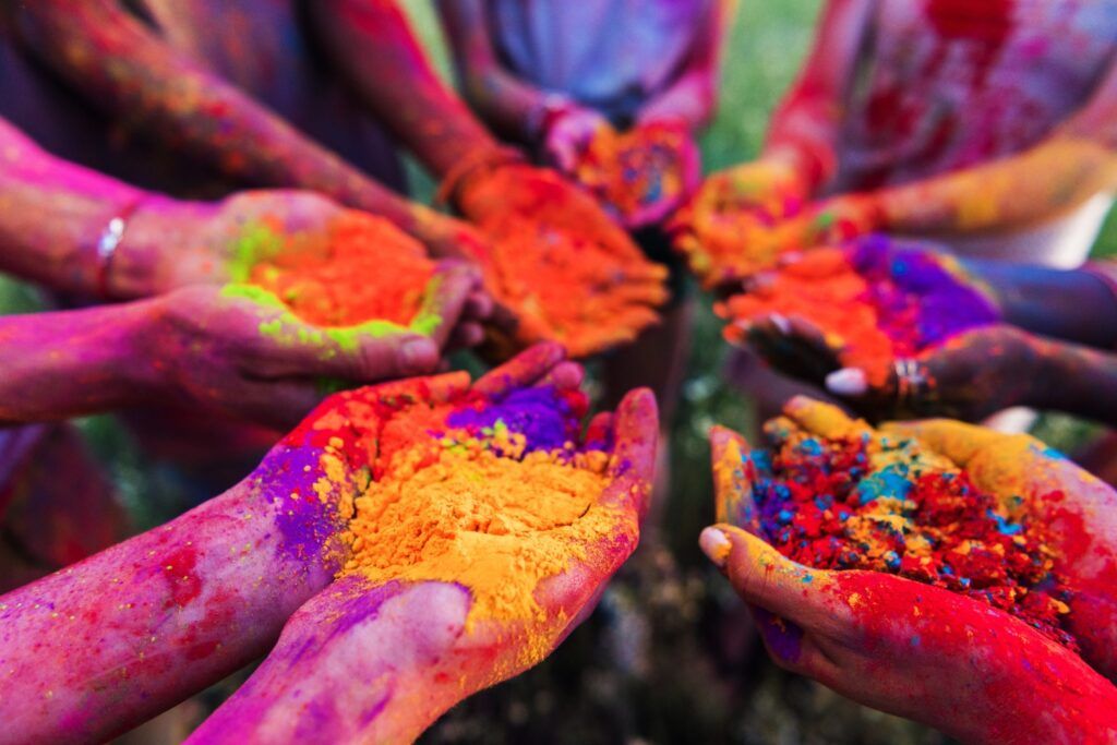 Manos llenas de polvos de colores brillantes durante la celebración del Holi en India, símbolo de alegría, unión y nuevos comienzos.