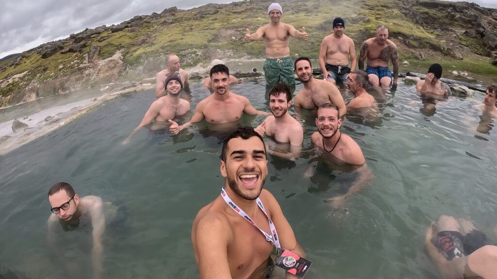 Grupo de viajeros WeRoad disfrutando de un baño geotermal natural y capturando el momento con un selfie.