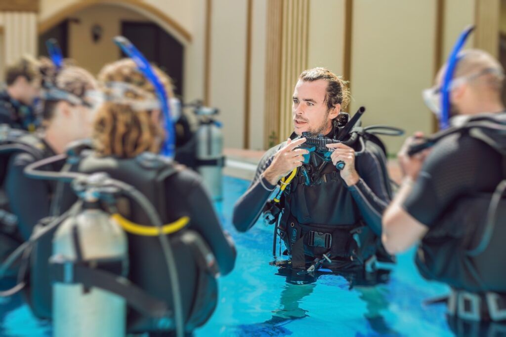 Instructor de buceo enseñando a un grupo de estudiantes en una piscina durante una clase práctica.