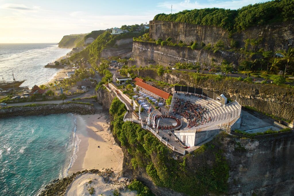 Anfiteatro en el acantilado de Uluwatu, Bali, con vistas a la playa y al océano durante el atardecer.