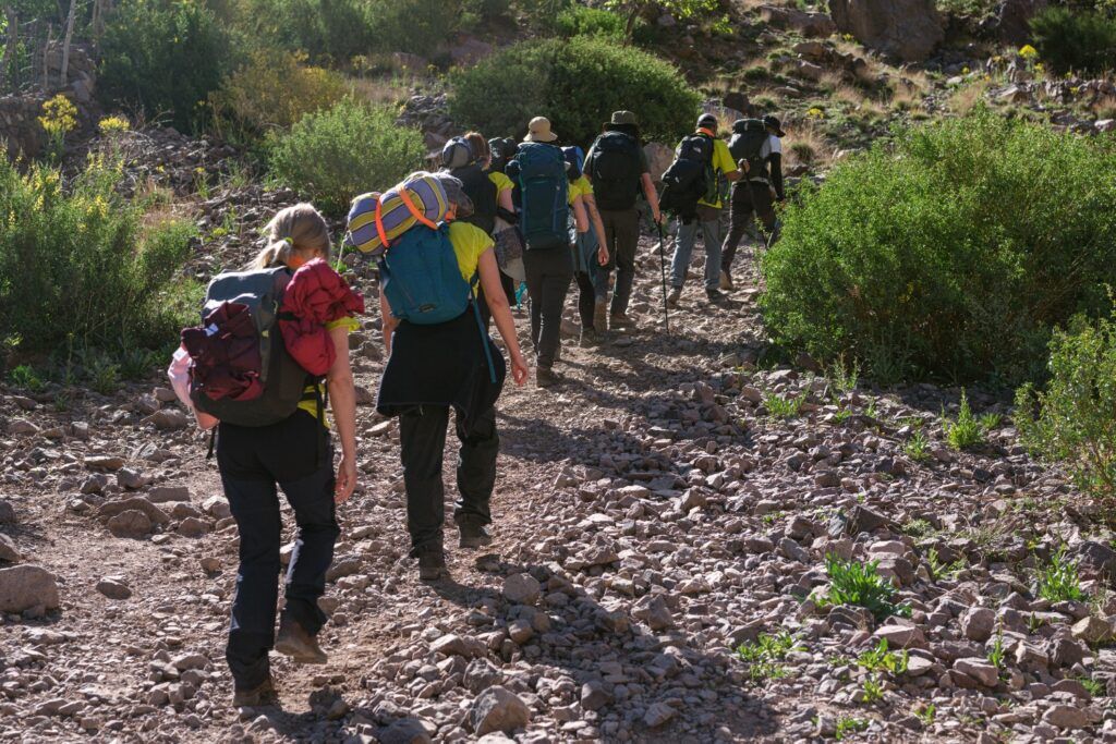Grupo de viajeros haciendo trekking por un sendero verde en las montañas del Atlas.