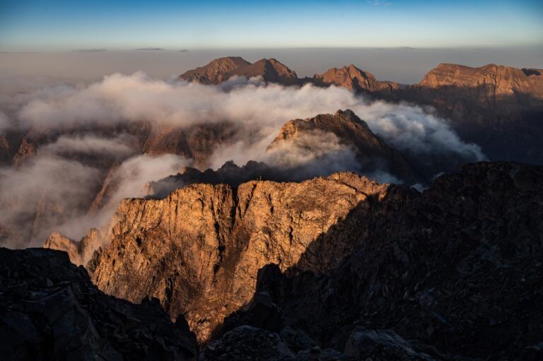 Vista desde una cima del Alto Atlas, con picos escarpados iluminados por el sol.