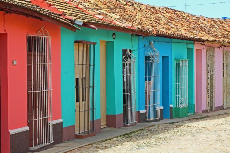 Casas coloniales coloridas con puertas enrejadas y techos de tejas en una calle empedrada de Trinidad, Cuba.