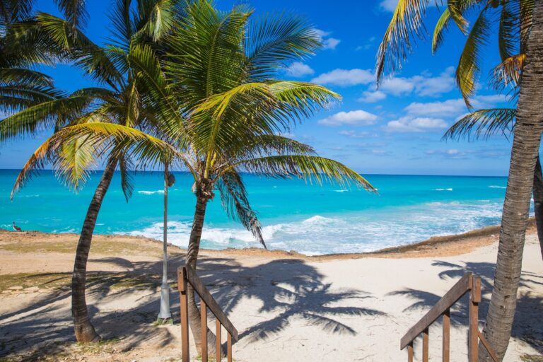 Escaleras de madera a la playa de arena blanca y palmeras en Varadero, Cuba.