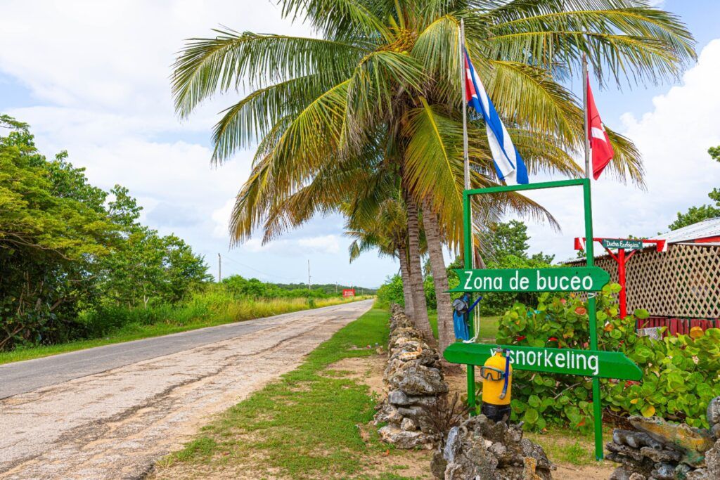 Carretera y cartel de buceo bajo palmeras en la provincia de Matanzas, Cuba.